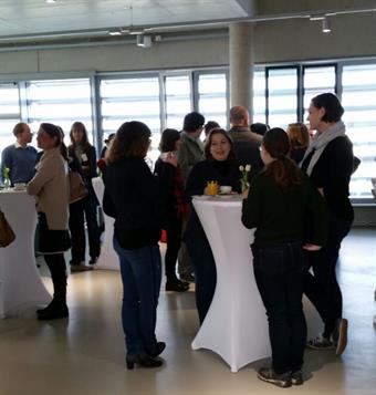 Teilnehmer des Treffen der Hochschuljuristen stehen um einen Stehtisch und besprechen sich.